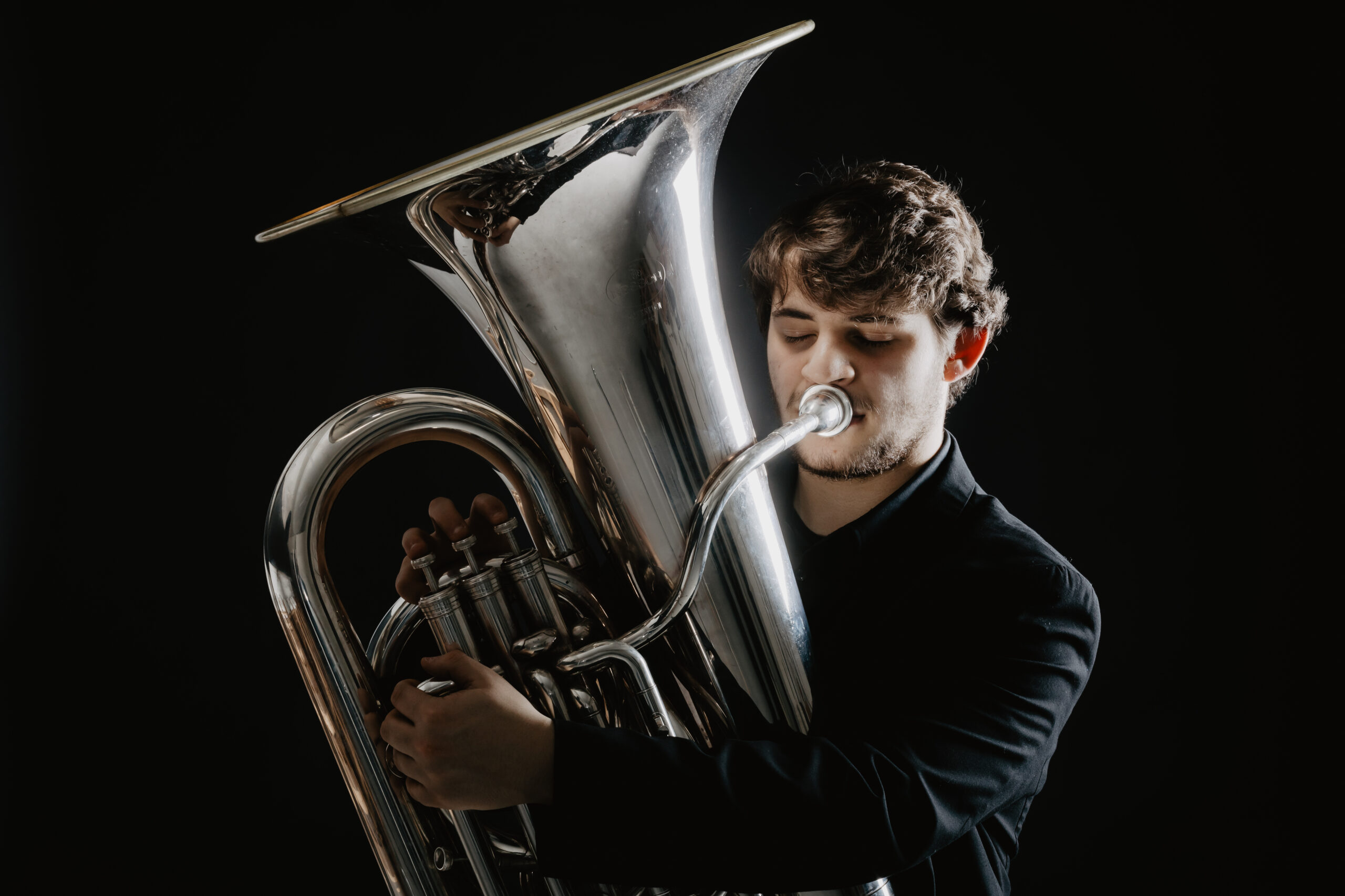 Gianmarino Strappati playing a tuba against a dark background